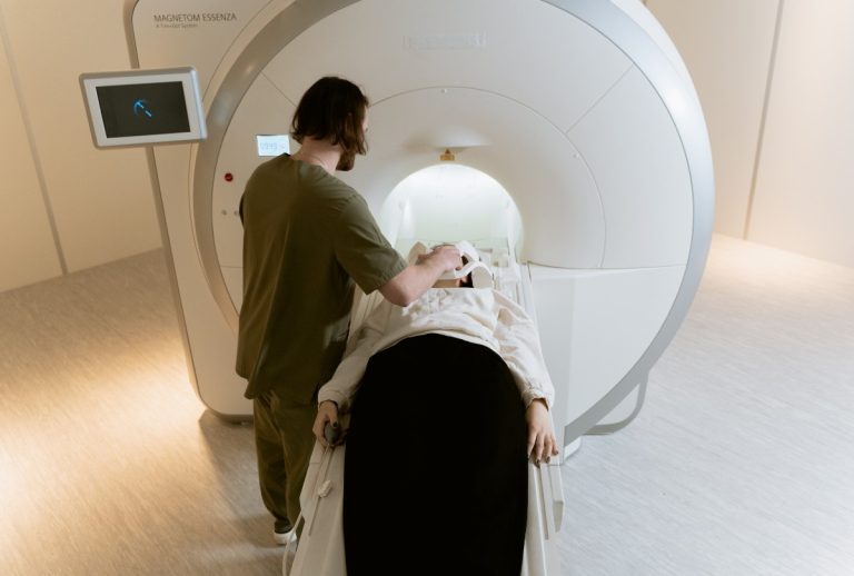 MRI Houston technician prepares patient for scan using advanced imaging system. Clean medical setting shown in detail.