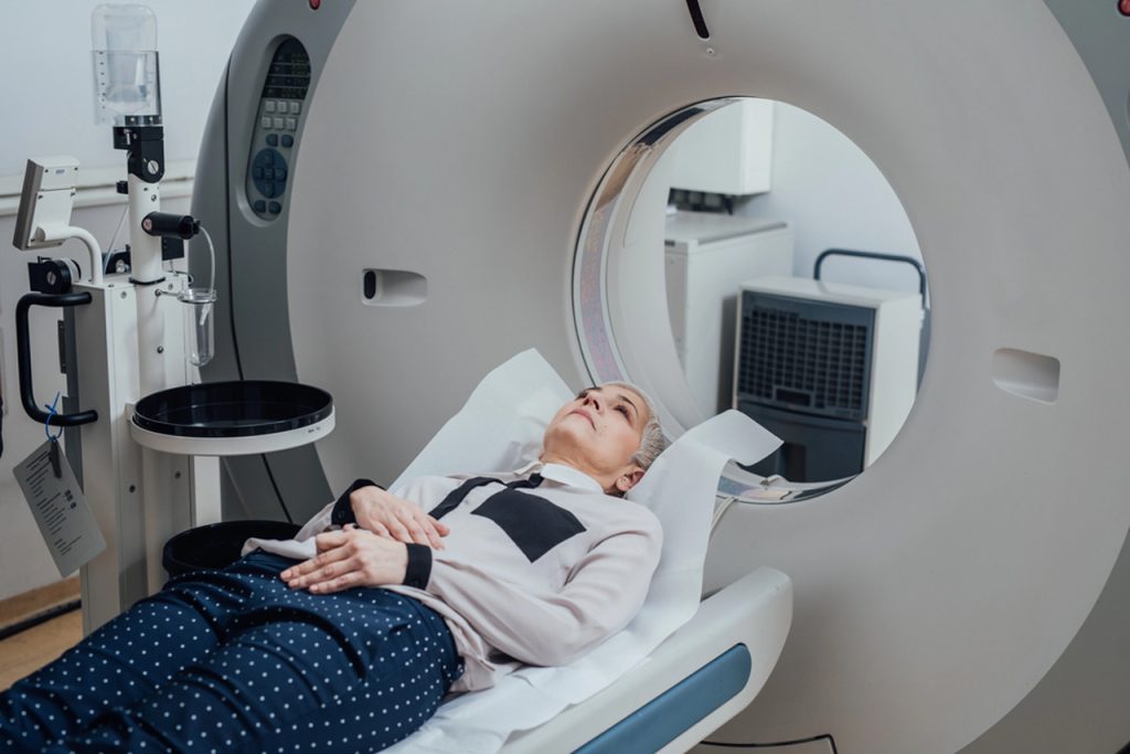 Senior woman lying on CT scanner bed during a comfortable walk-in CT scan procedure in Houston medical imaging center.