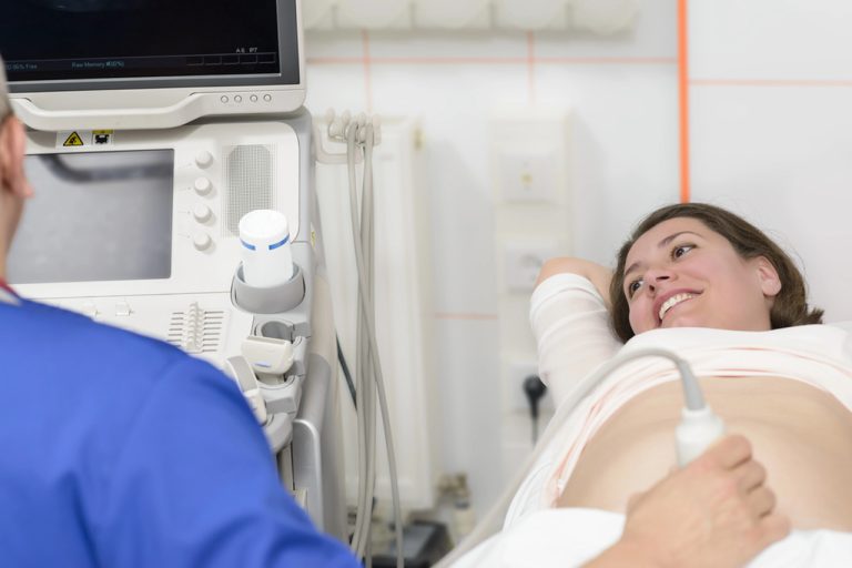 3D ultrasound Houston prenatal appointment with smiling pregnant woman and technician using abdominal ultrasound machine in modern office