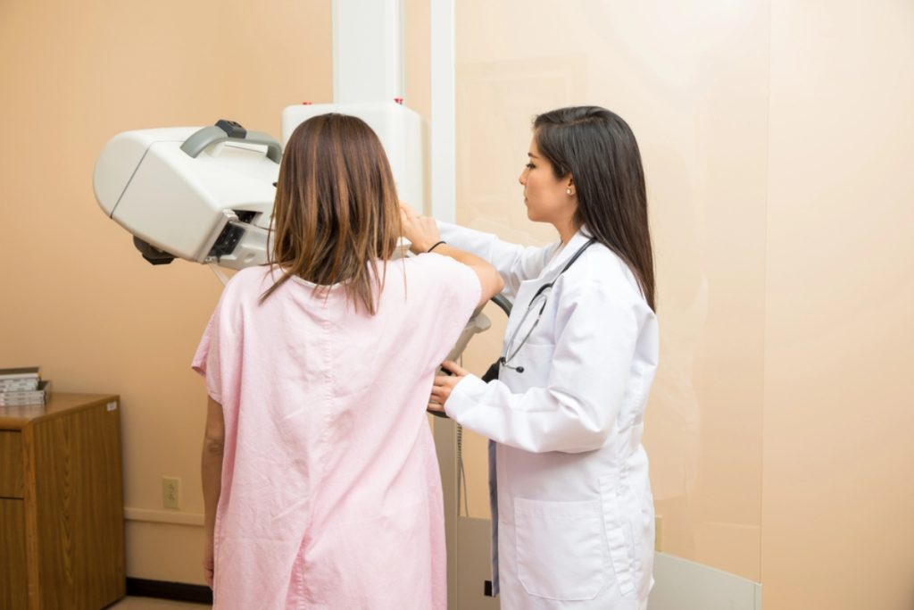 A technologist positions a woman for a mammogram, a screening that can lead to a diagnostic breast ultrasound in Houston.