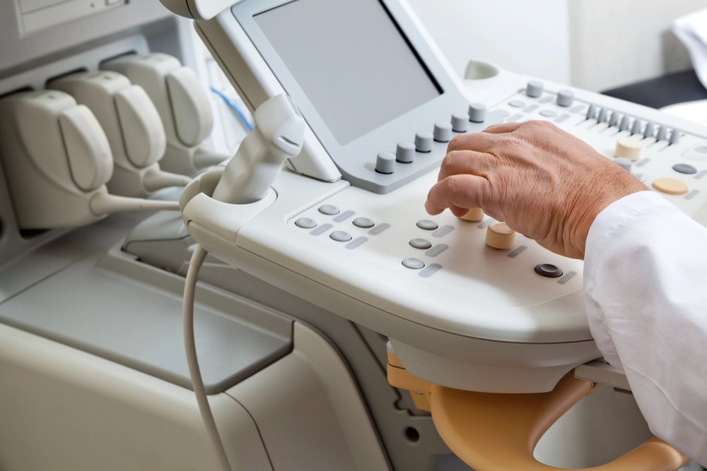 Close-up view of a technician's hand adjusting the controls on a machine during a cheap ultrasound houston exam.
