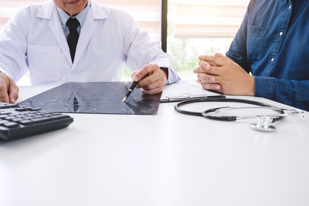 Doctor and patient consult on diagnostic results from cheap CT scans in a Houston clinic, reviewing images on a desk.