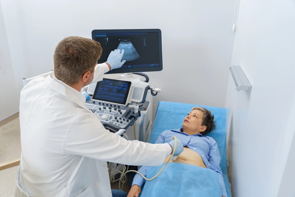 A male doctor performs an abdominal scan on a female patient, part of a cheap ultrasound houston diagnostic service.