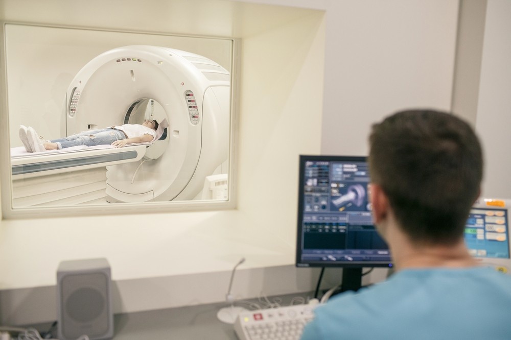 A Houston technologist looks through a window as a patient is scanned, providing expert mri services houston.