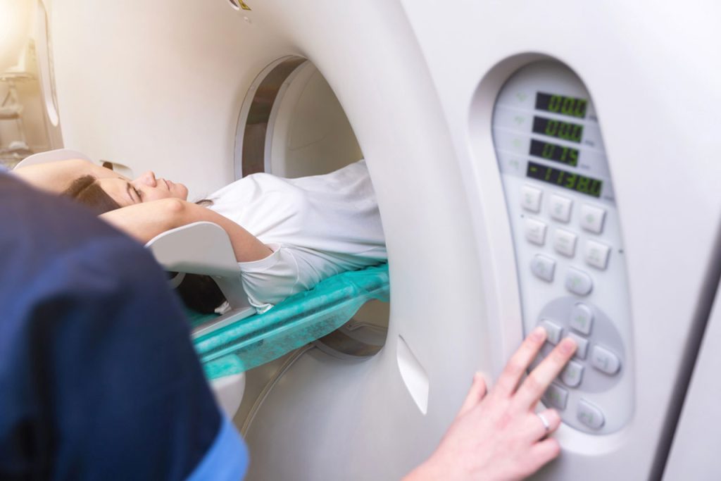 An MRI Houston technologist uses the control panel to set up a scan for a patient inside the machine.