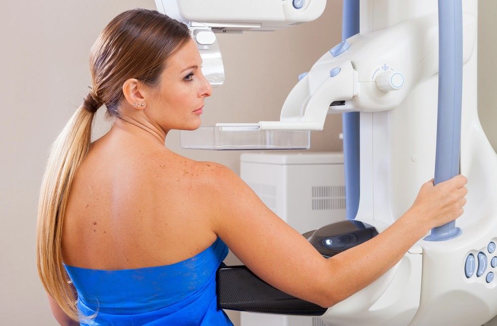 A patient prepares for a breast exam on a professional mammography machine at our mammogram services houston location.