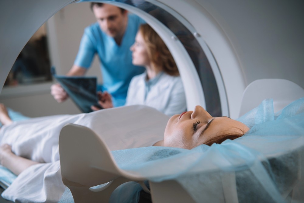 Patient preparing for a scan at a walk-in MRI Houston clinic while doctors review medical imaging charts.