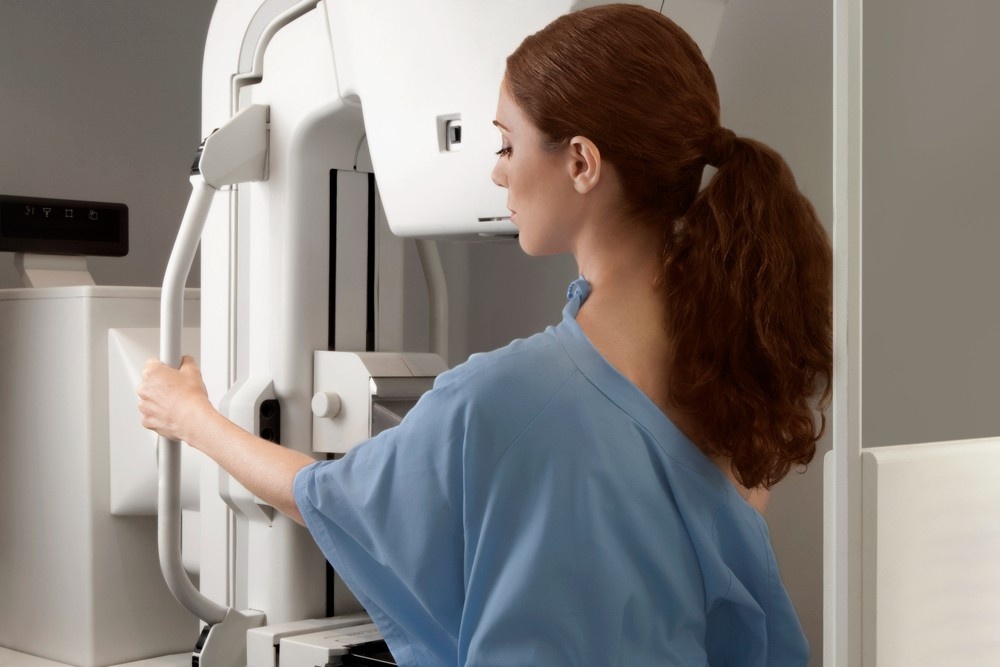 A patient receives breast cancer screening on a mammography machine at a clinic offering mammogram services houston.
