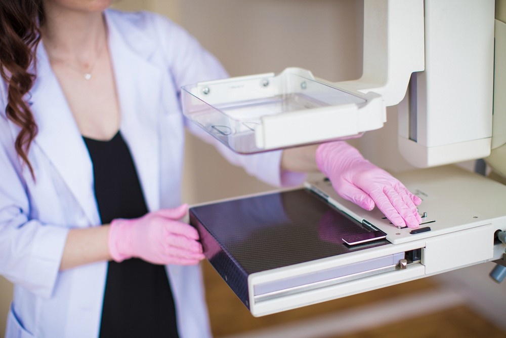 A technician with pink gloves prepares a digital mammography machine at a center providing mammogram services houston.